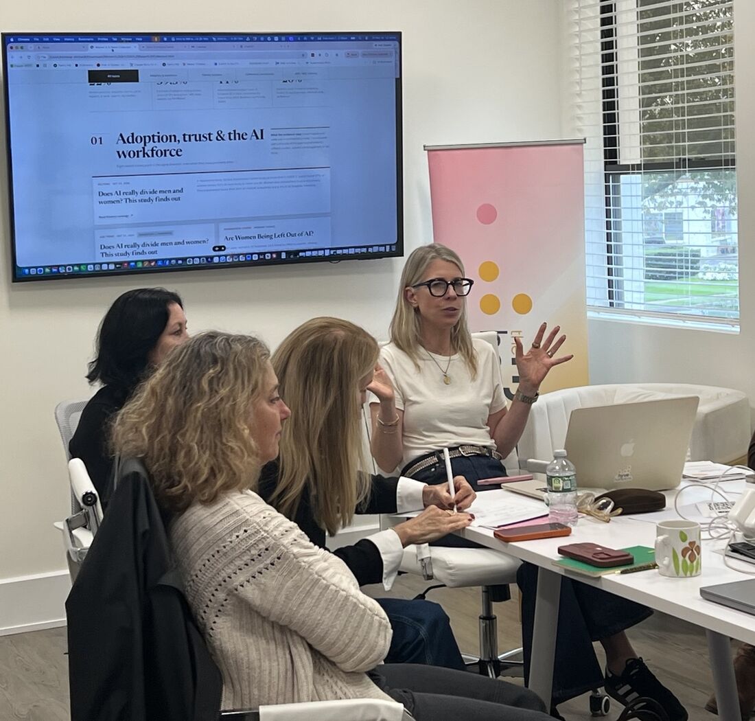 Kim leading a working session at a table with women and laptops